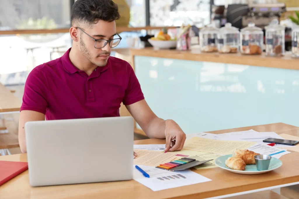 Person reviewing prescription documents and paperwork while using a laptop to understand the medication ordering process